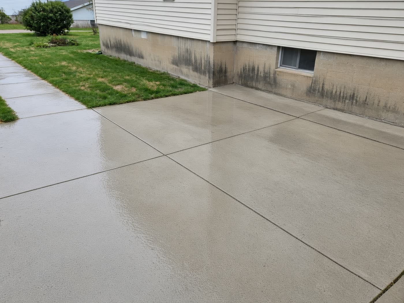 Freshly cleaned concrete driveway beside a house