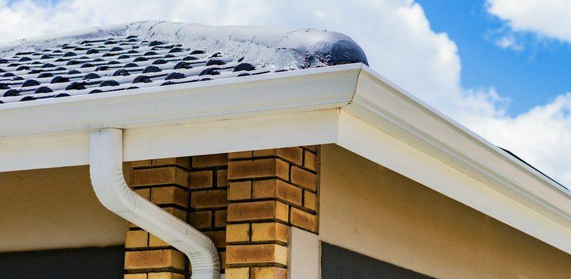 Clean white gutter and downspout on a brick corner